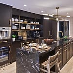 Modern kitchen with dark wood cabinets, marble countertops, gold accents, and built-in appliances.