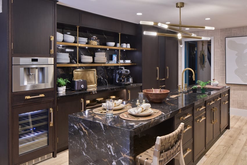 Modern kitchen with dark wood cabinets, marble countertops, gold accents, and built-in appliances.