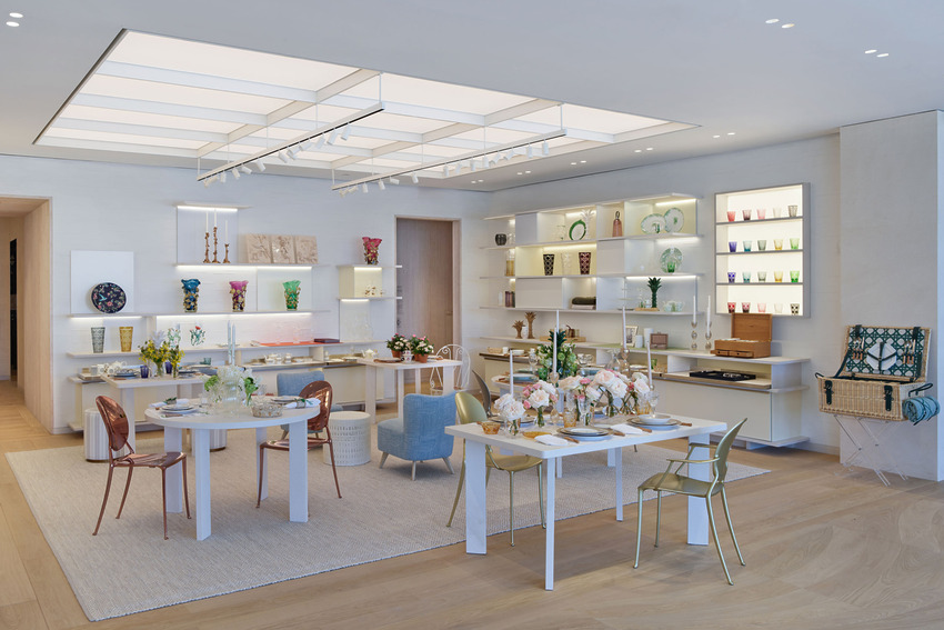 Modern dining area with wooden floor, white tables, colorful chairs, decorative shelves, and elegant table settings.