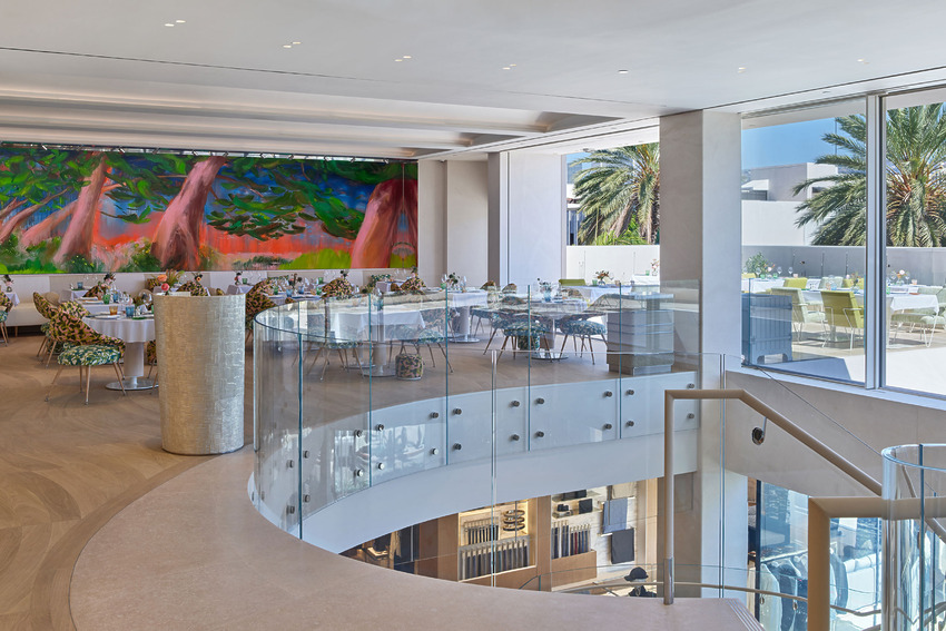 Modern restaurant interior with colorful mural, large windows, and elegant dining area with spiral staircase and outdoor view.
