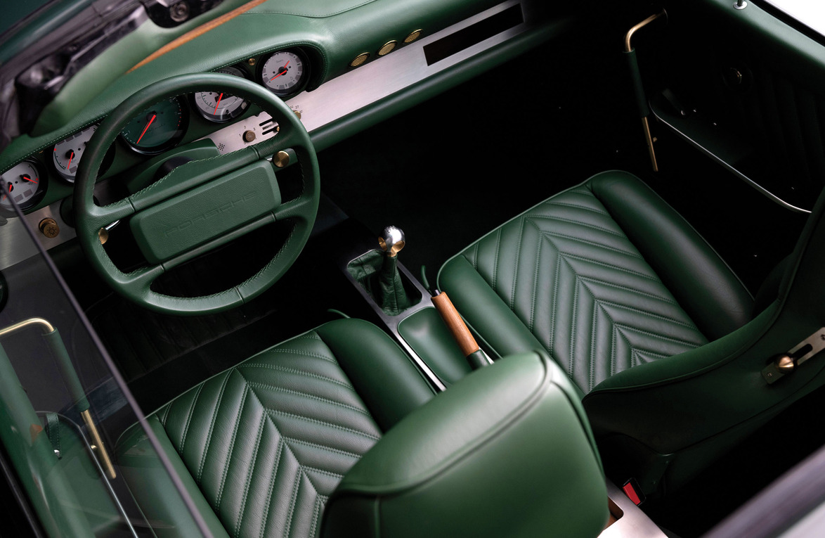 Vintage car interior with green leather seats, dashboard, and steering wheel, featuring retro gauges and manual gear shift.