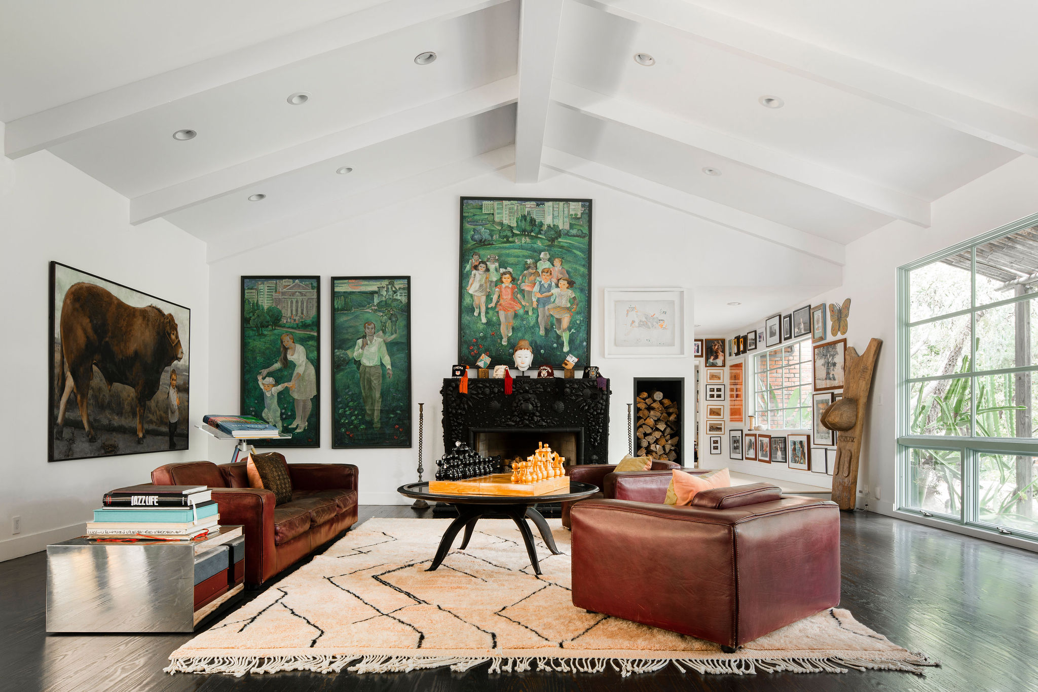 Spacious living room with large paintings, leather sofas, chessboard on round table, and modern decor.