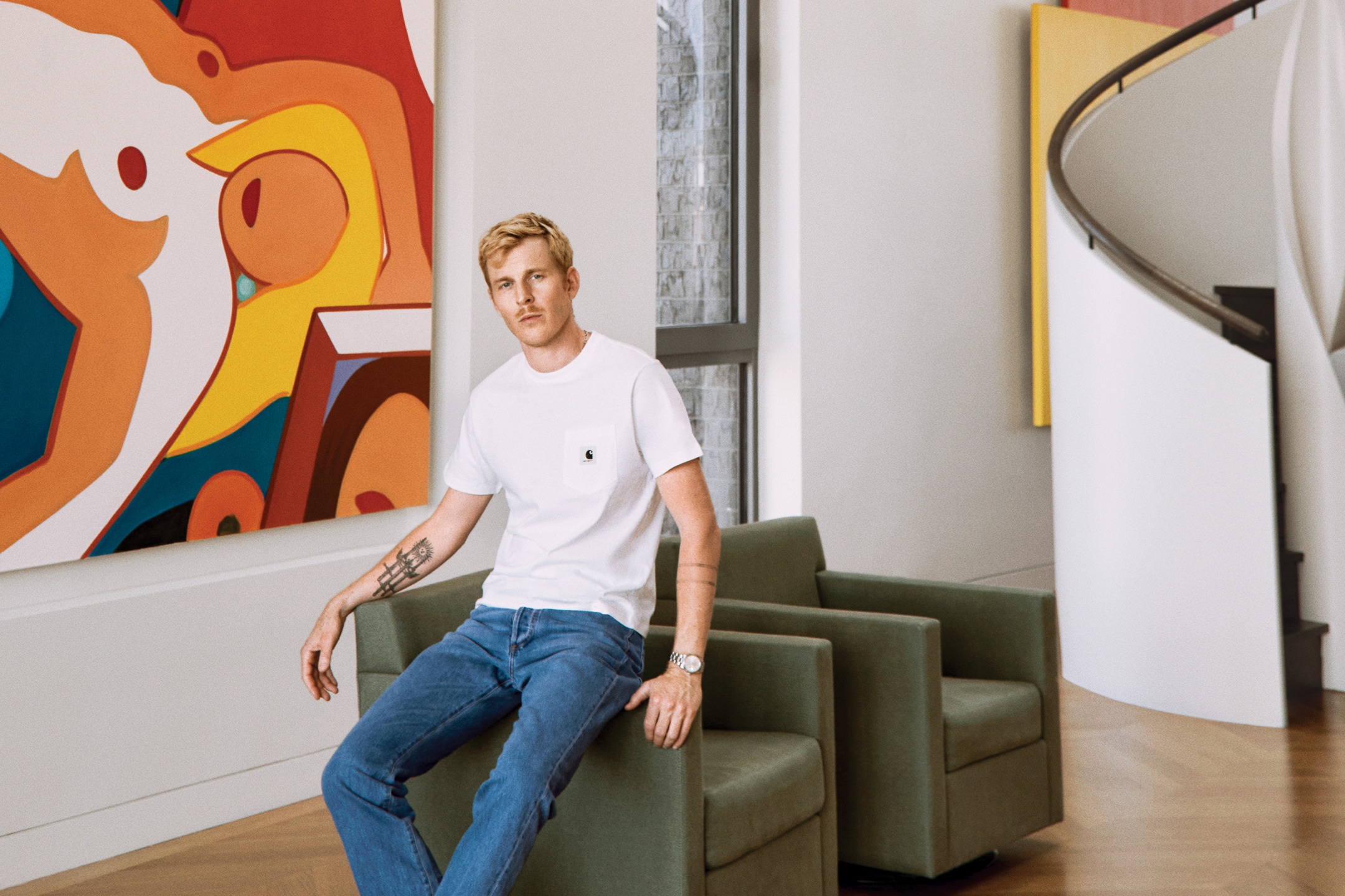 Person sitting on a green chair in a modern room with colorful abstract art on the wall.