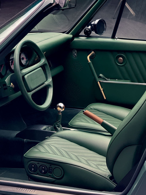 Vintage car interior with green leather seats and manual gear shift.
