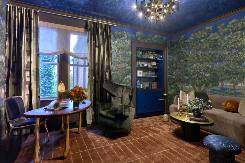 Luxurious living room with blue and green forest-themed wallpaper, velvet chairs, and a modern chandelier on a starry ceiling.