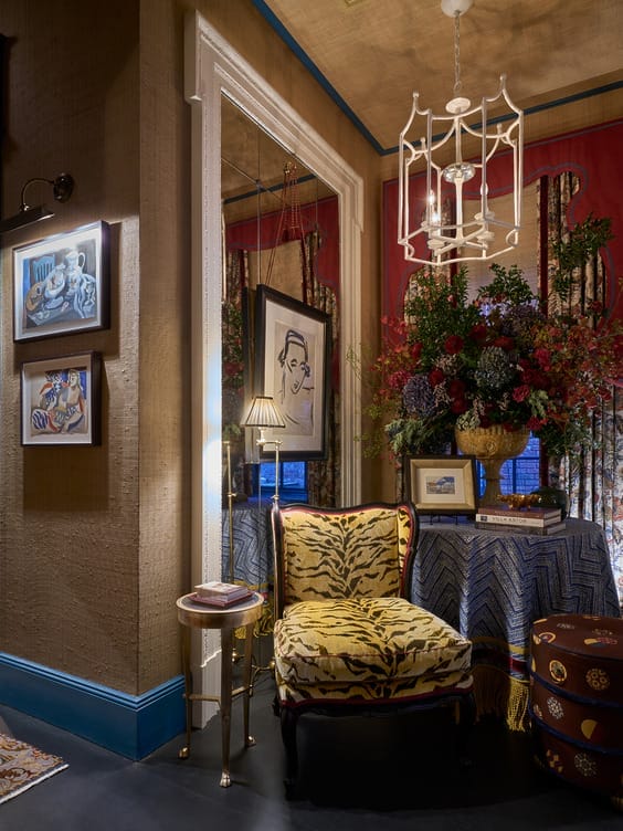 Elegant reading nook with patterned chair, framed art, and a table adorned with a vibrant floral arrangement and table lamp.
