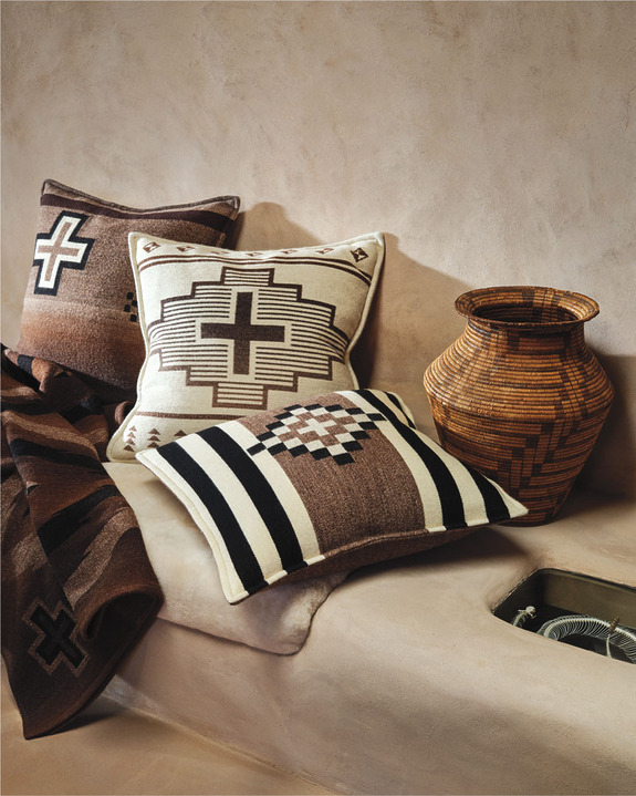 Patterned pillows and a woven basket on a textured surface, featuring earthy tones and geometric designs.