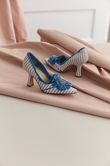 Blue and white striped high heels with blue bows on a pink fabric background.