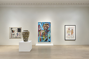 Art gallery exhibit featuring colorful paintings, intricate drawings, and a decorative vase on display in a minimalist setting.