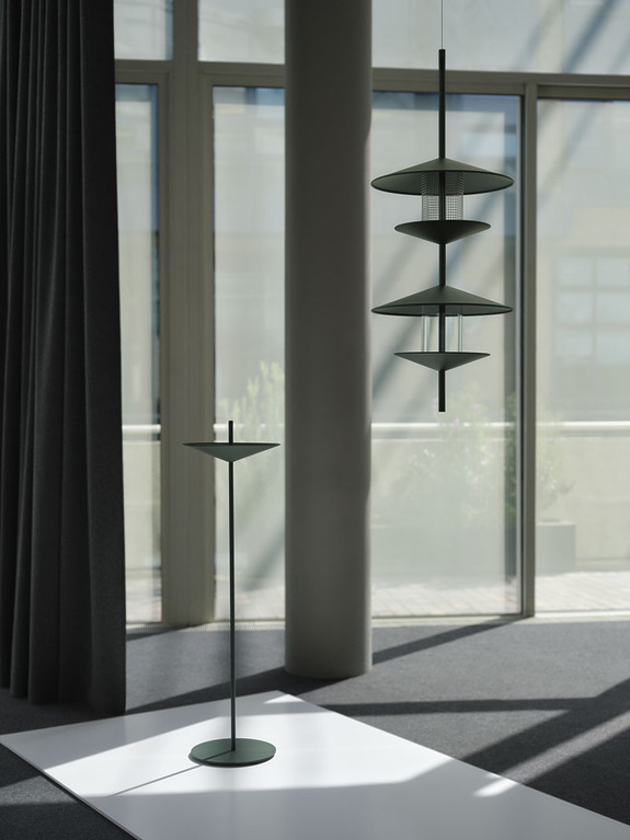 Modern minimalist floor and hanging lamps in a sunlit room with large windows and dark curtains.