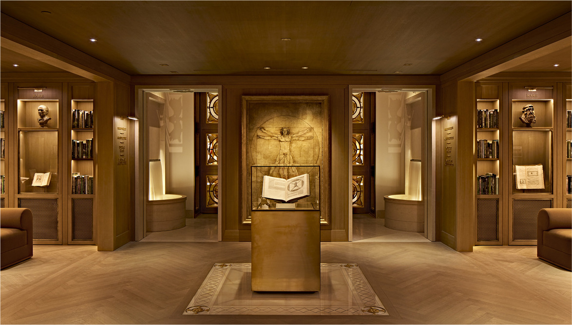 Luxurious library with wooden shelves, open book on a pedestal, and Da Vinci's Vitruvian Man artwork in a warm-lit room.