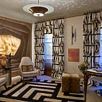 Modern living room with patterned curtains, geometric rug, and stylish chairs.