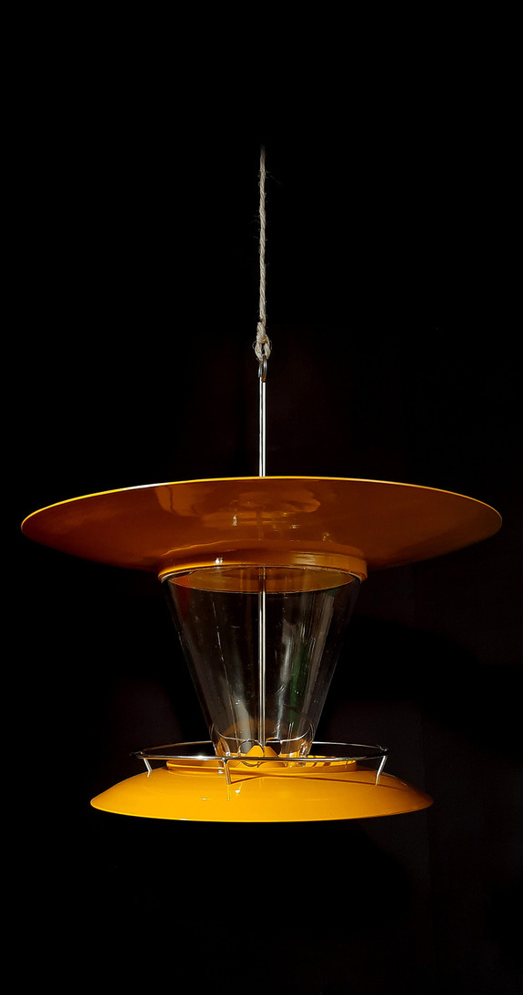 Orange and clear modernist pendant light against a black background, showcasing its unique double-layered design.