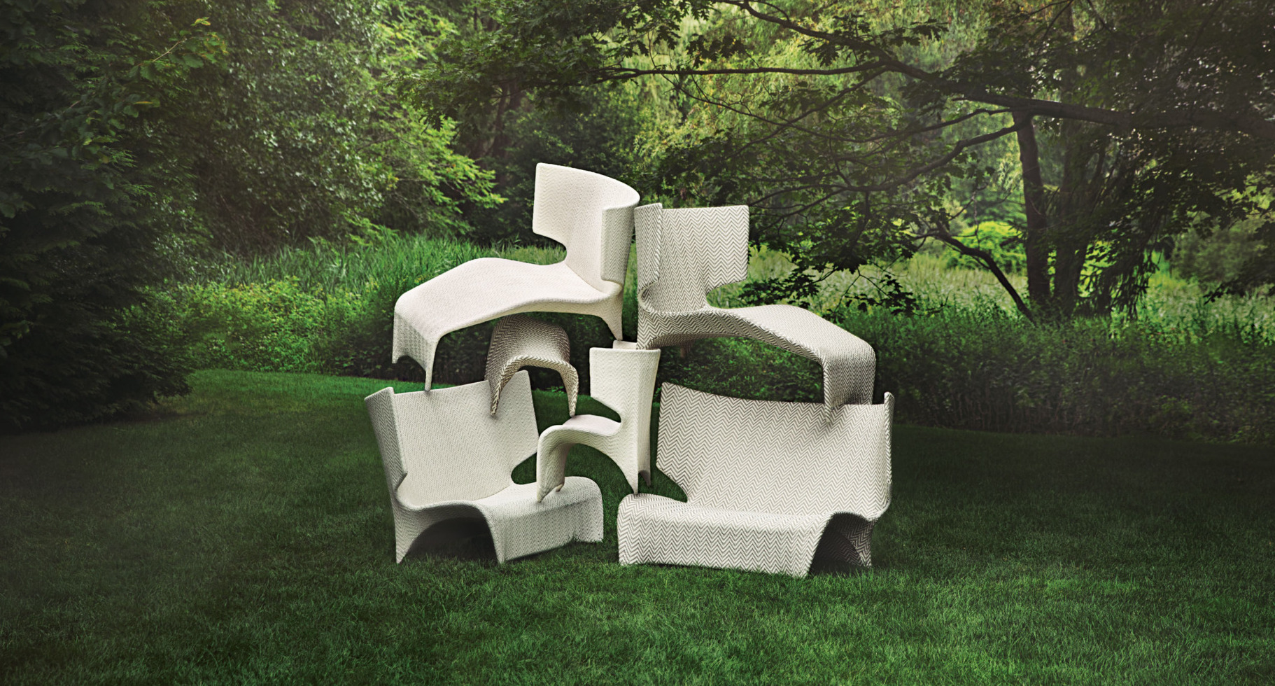 Stacked white chairs on a lush green lawn with trees in the background