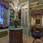 Luxurious vintage-style dressing room with floral decor, ornate chandelier, wooden vanity, and a bouquet on a round table.