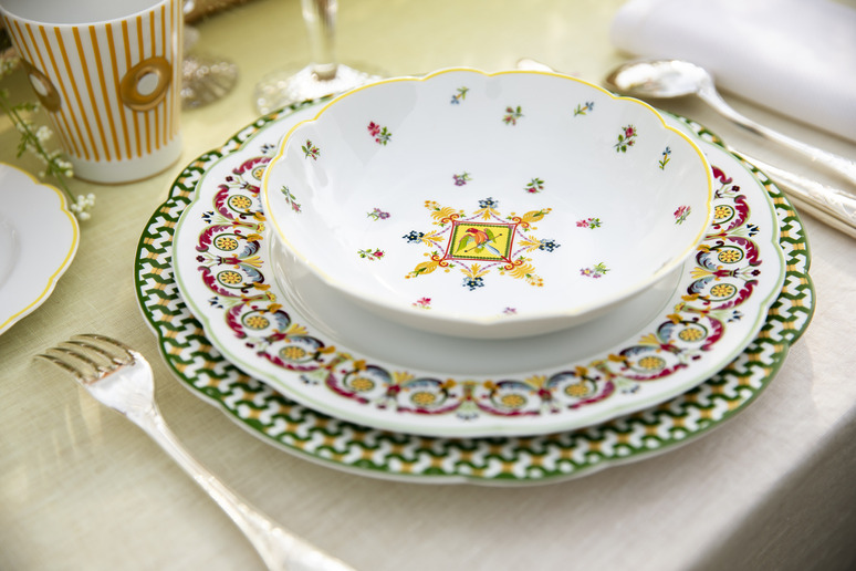 Elegant table setting with decorative plates and silver cutlery on a light tablecloth.
