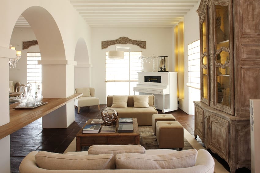 Elegant living room with neutral-toned furniture, arched doorways, and a white piano in a bright, spacious setting.