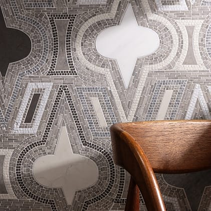 Geometric patterned wallpaper with abstract shapes in shades of gray behind a wooden chair.