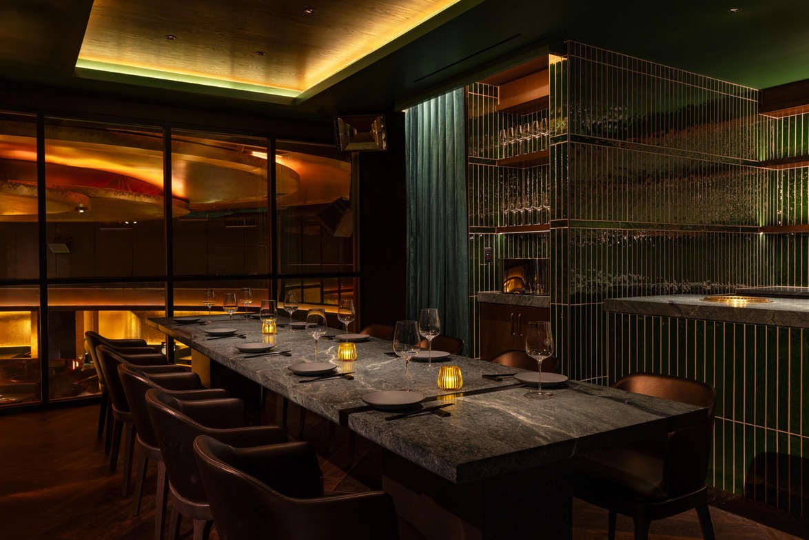 Dimly lit modern restaurant interior with elegant wooden furniture, set table, and ambient lighting.