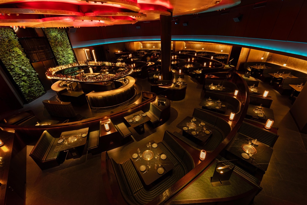 Luxurious restaurant interior with modern design, circular bar, dim lighting, and plant-covered walls creating an elegant atmosphere.