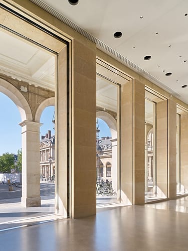 Spacious modern interior with large windows overlooking historic architectural arches and a clear blue sky outside.