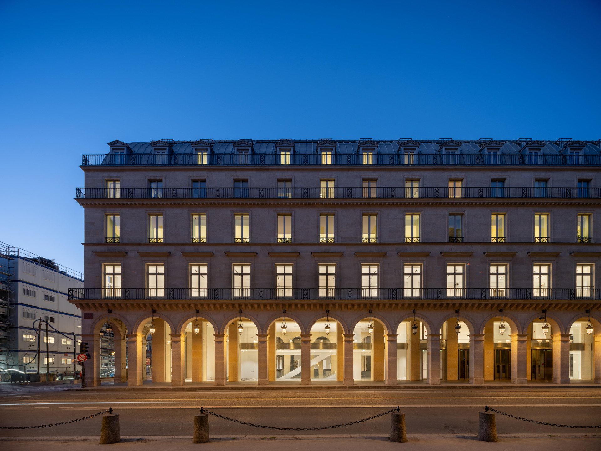 Illuminated historic building with arched windows and elegant facade at dusk, featuring a calm street view in front.