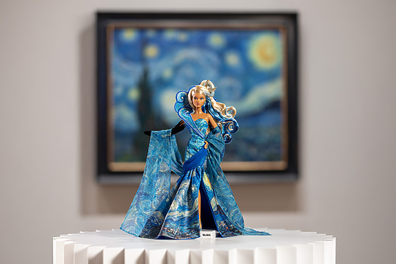 Barbie doll in a flowing, starry blue dress inspired by Van Gogh's Starry Night, with the painting in the background.