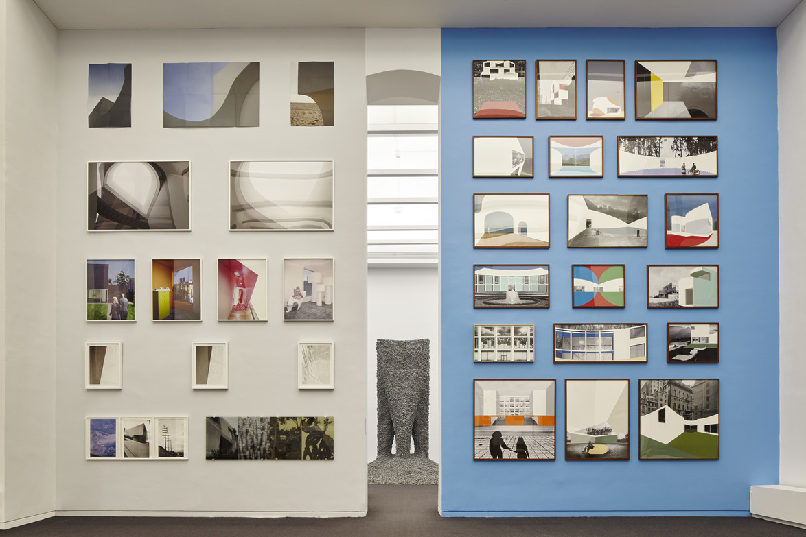 Gallery wall with various framed abstract art pieces on blue and white walls, and a sculpture visible in the background.