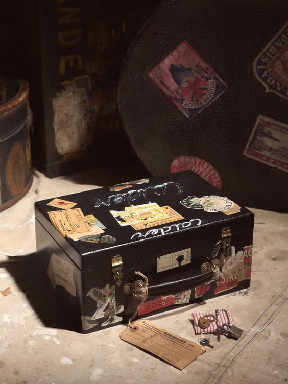 Vintage suitcase with travel stickers, lying on a floor with scattered travel tags around it.