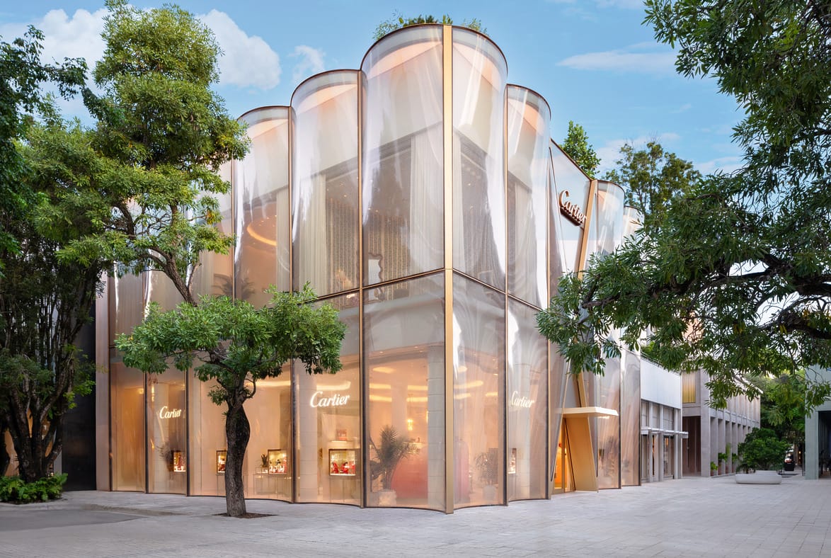Modern building with a unique cylindrical design, surrounded by trees, set against a clear blue sky.