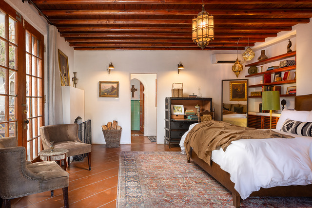 Cozy bedroom with rustic decor, wooden ceiling beams, vintage furnishings, and soft lighting, creating a warm and inviting atmosphere.