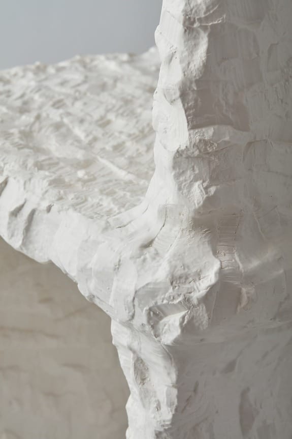 Close-up of a textured, white stone sculpture with chiseled surfaces and abstract shapes.