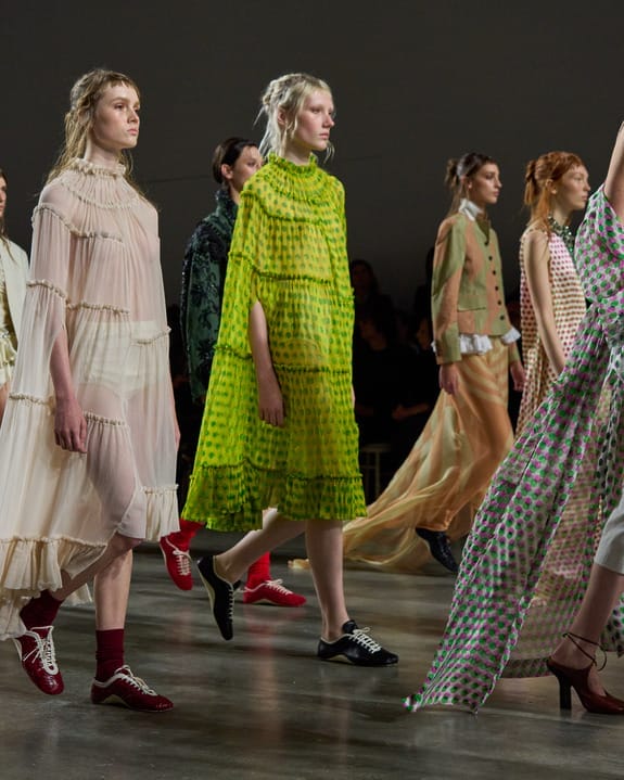 Models walking on a fashion runway wearing colorful and patterned outfits with various textures and styles.