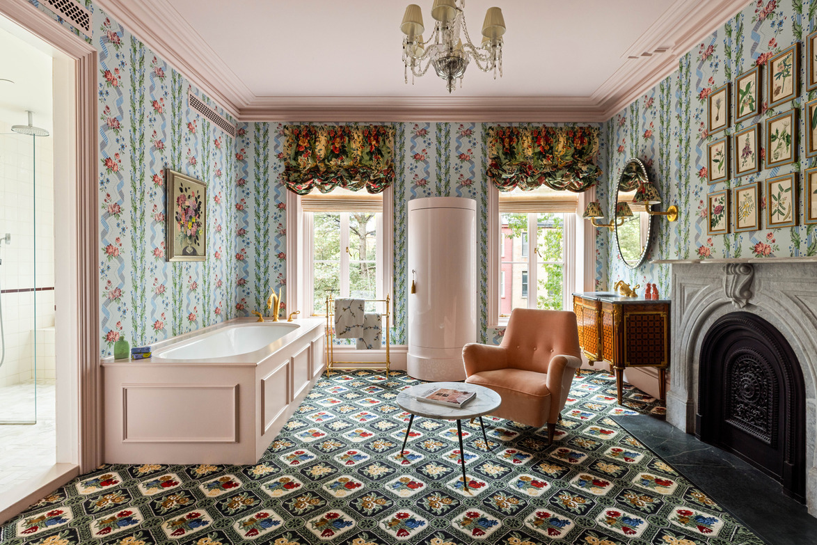Luxurious vintage bathroom with floral wallpaper, elegant bathtub, vintage fridge, armchair, and ornate fireplace.
