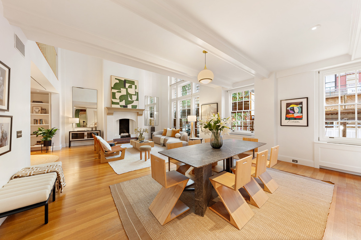 Spacious modern dining and living area with wooden floors, large windows, abstract art, and contemporary furniture.