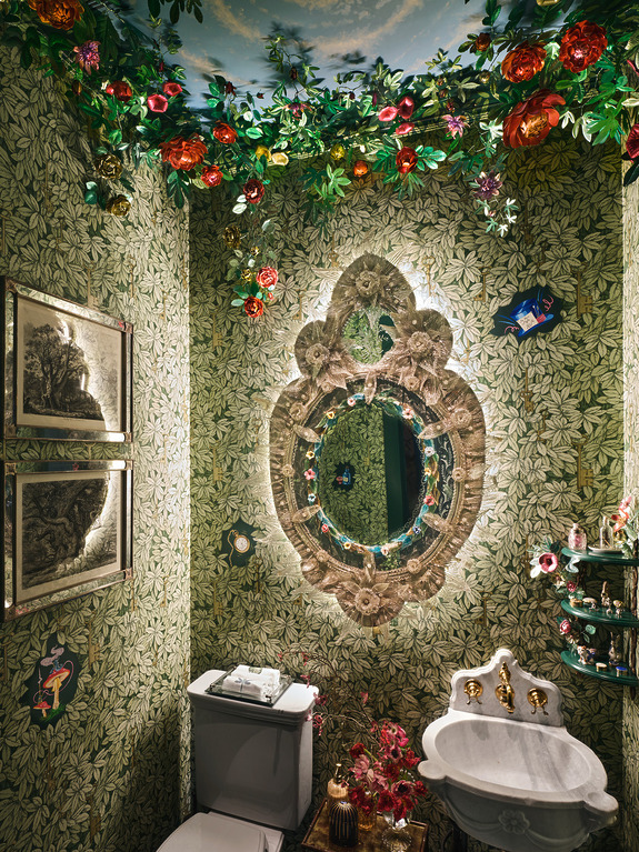 Ornate bathroom with floral wallpaper, decorative mirror, and lush greenery adorning the ceiling for a whimsical touch.