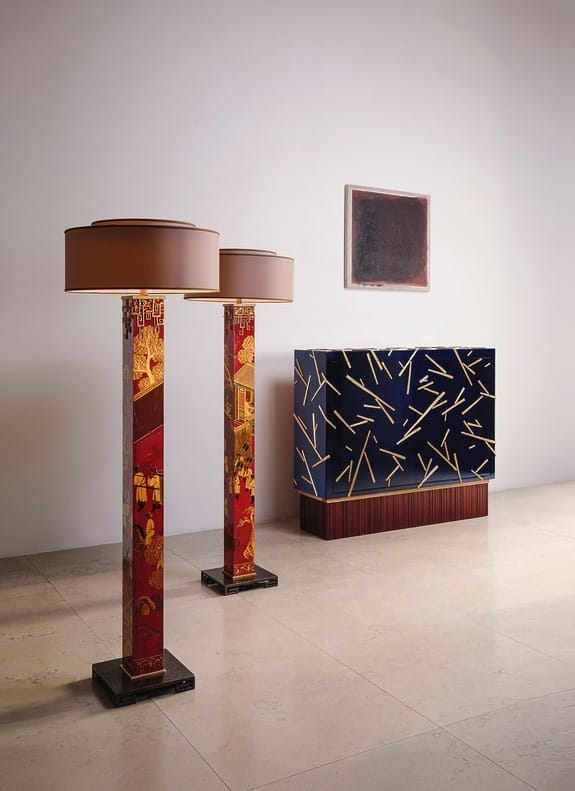 Two decorative lamps with red and gold designs beside a blue patterned cabinet in a minimalist room setting.