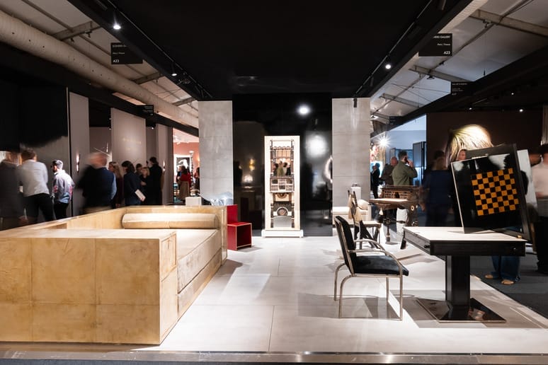 Modern art gallery exhibit with contemporary furniture and people walking around, featuring a chessboard display.