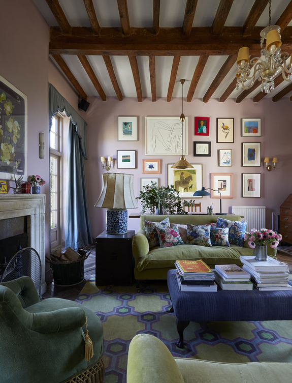 Eclectic living room with colorful art on walls, a green sofa, floral pillows, and a variety of decorative elements.