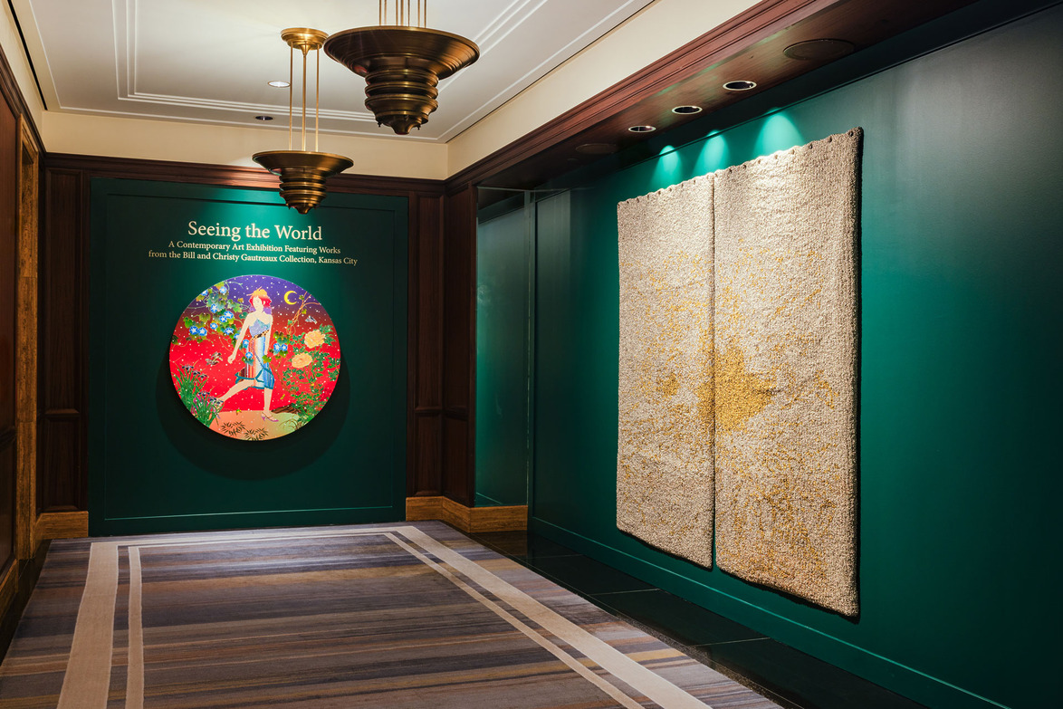 Art exhibition entrance with circular colorful artwork on left wall and textured beige panels on right wall.