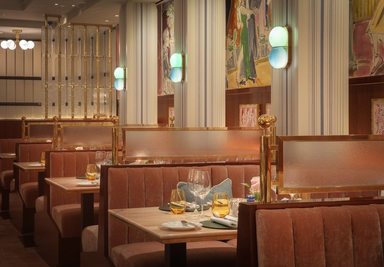 Elegant restaurant interior with plush booth seating, set dining tables, and modern decor featuring warm lighting.