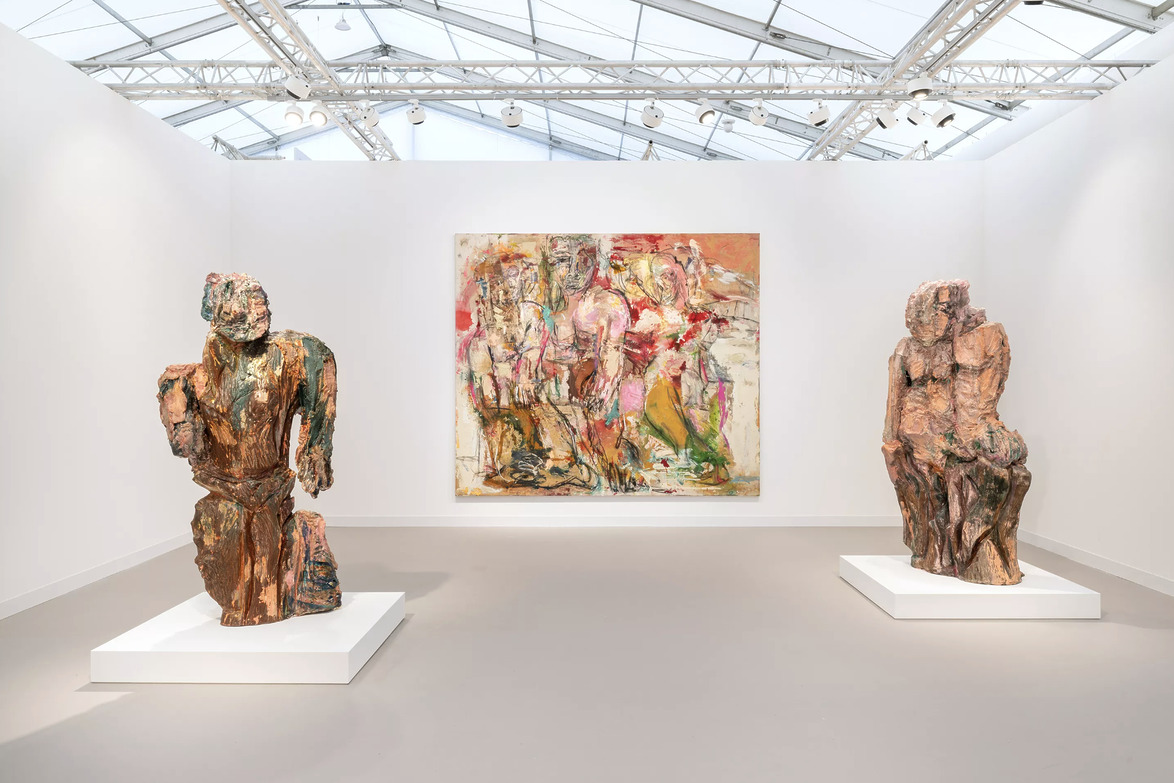 Art gallery with two abstract bronze sculptures on white pedestals and a colorful abstract painting on the back wall.