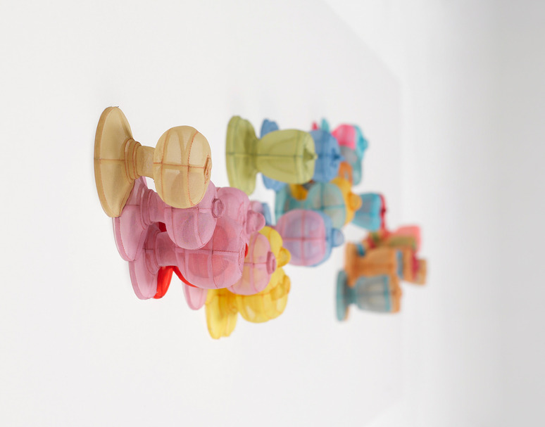 Colorful, translucent toy figures standing in a row on a reflective white surface, casting soft shadows.