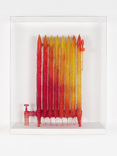 Colorful yarn art sculpture resembling a radiator in a white display case.