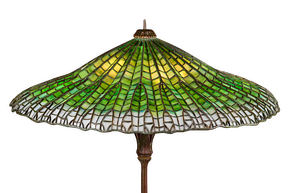 Green stained glass lampshade with intricate patterns on a vintage lamp base.