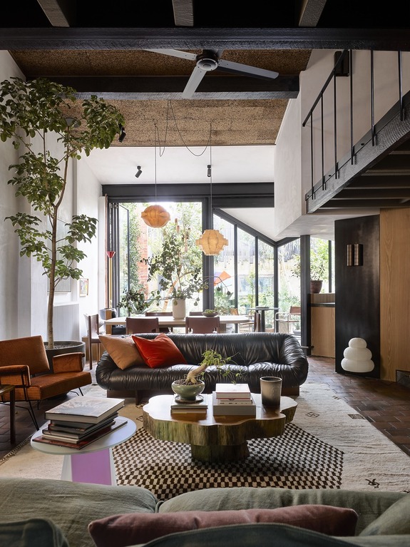 Modern living room with stylish furniture, indoor plants, large windows, and natural light creating a cozy atmosphere.