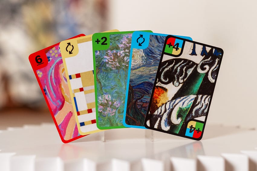 Colorful cards with artistic designs stand on a white surface, featuring numbers and multi-colored borders.