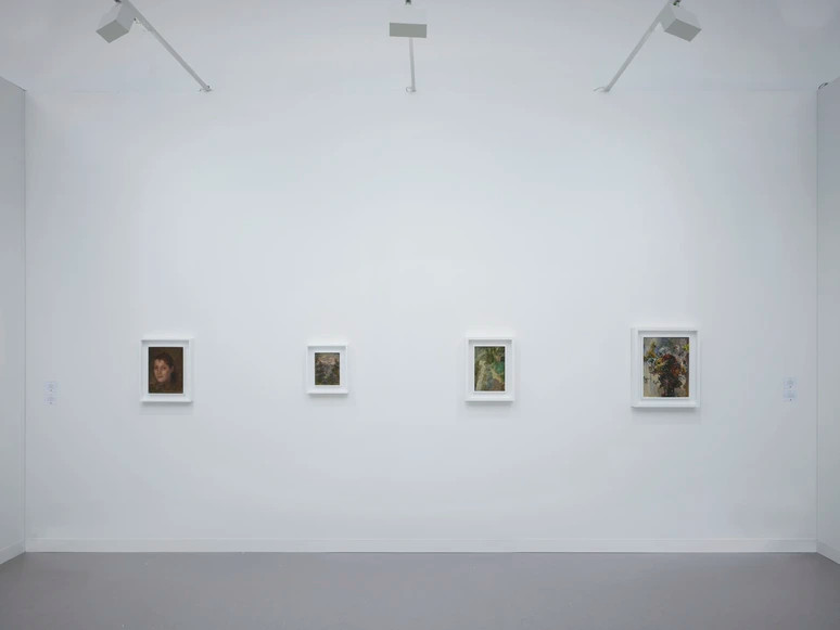 Art gallery interior with four framed paintings evenly spaced on a white wall under bright ceiling lights, minimalist design.