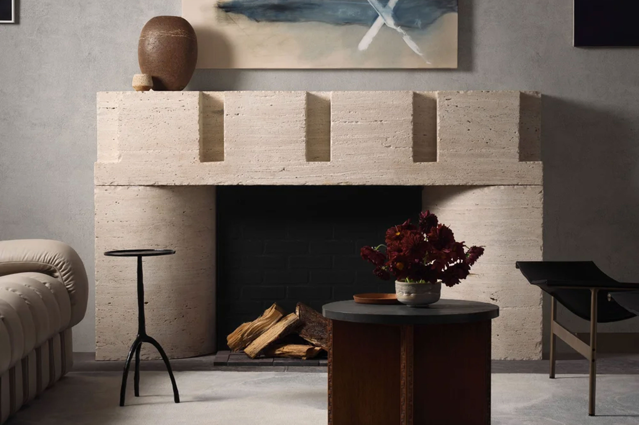 Modern living room with a minimalist fireplace, decorative vase, abstract painting, and stylish furniture.