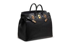 Black luxury handbag with gold hardware and two handles, shown on a plain background.